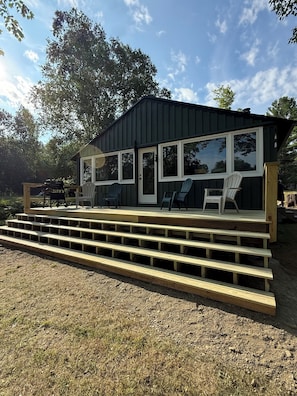 A small, single-story building with a porch, outdoor seating, and a view of the surrounding landscape.