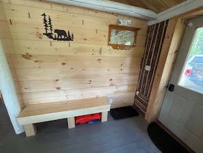A wooden interior with a bench, a mirror, and a license plate sign.