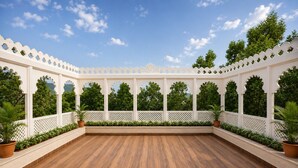 Un área exterior amplia con piso de madera, paredes de celosía blanca y plantas en macetas.