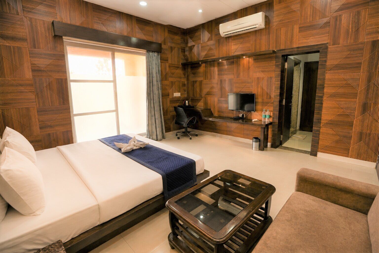 Habitación de hotel con cama, escritorio, televisión y zona de estar.