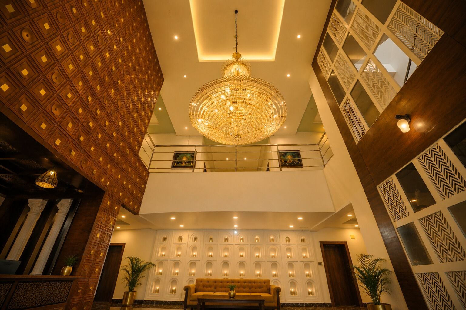 A lobby with a chandelier, a sofa, and patterned walls.