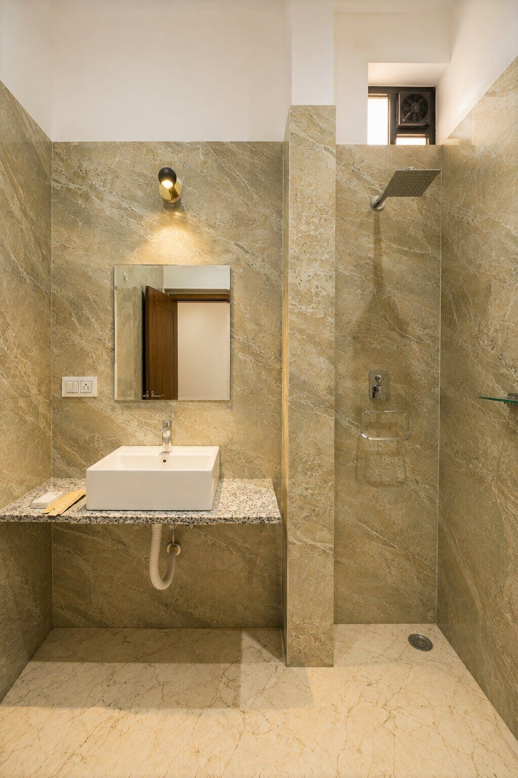 Un baño con lavamanos de mármol, espejo, ducha y ventilador de techo.