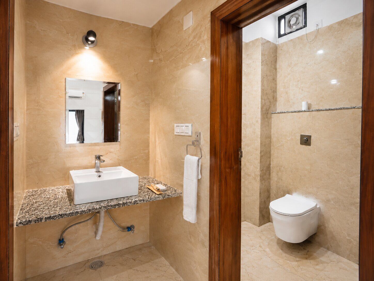 Un baño con lavamanos, espejo, toallero y retrete.