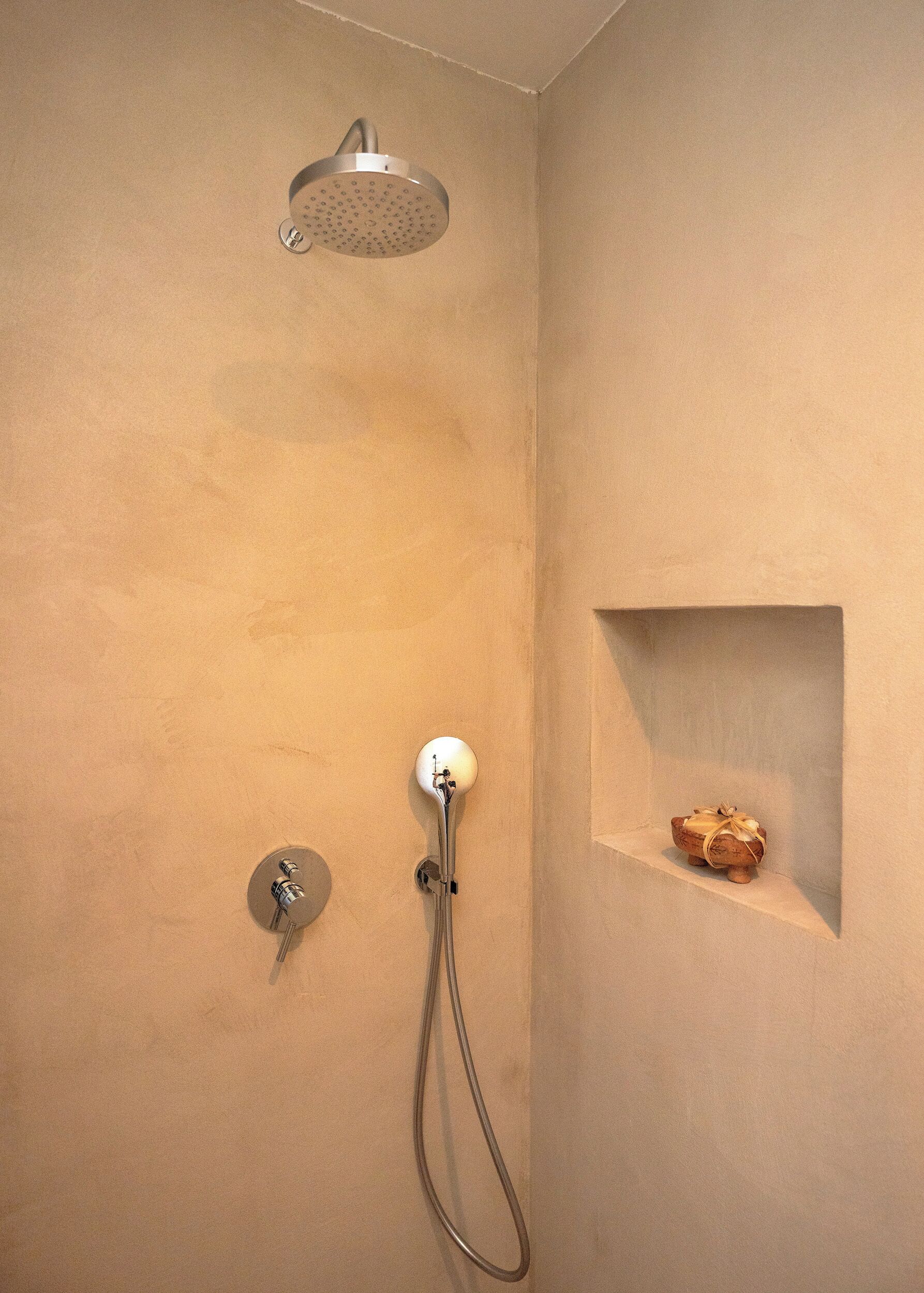 Casa de banho com chuveiro, porta-toalhas e uma pequena prateleira com um objeto decorativo.