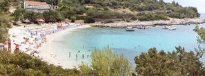 A coastal beach with clear water, beach umbrellas, and boats. - Beachfront Villa Atropos (Hvar)