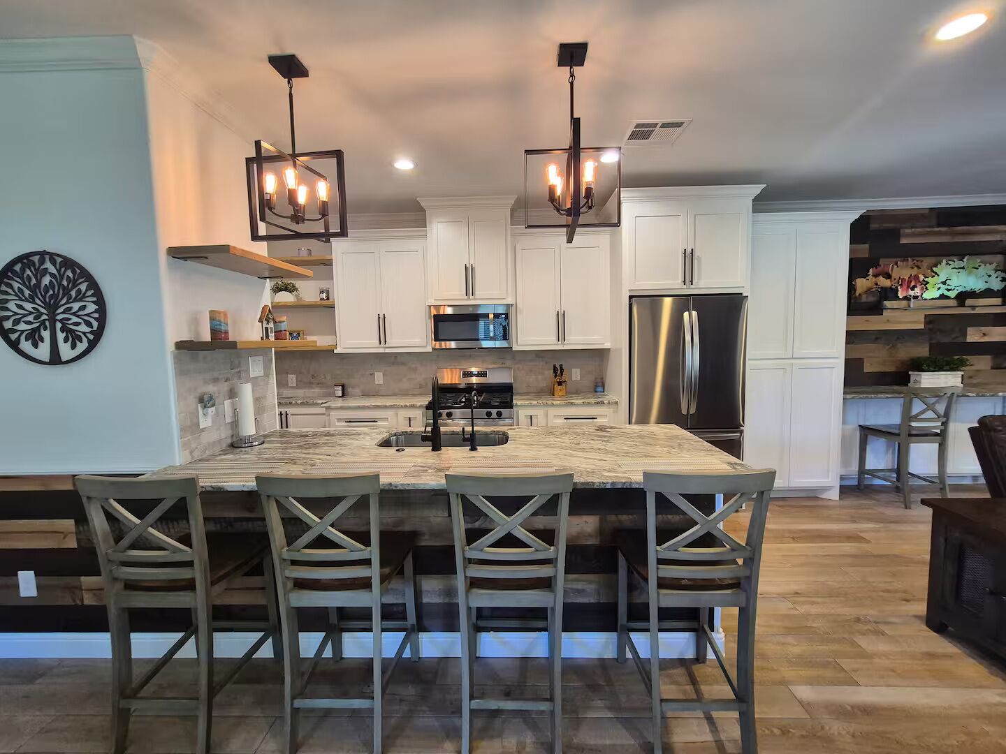 A modern kitchen with a large island, stainless steel appliances, and pendant lighting.