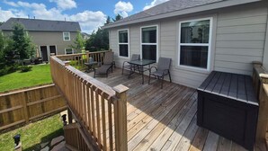 Een terras met buitenmeubilair, een barbecue en uitzicht op een woonwijk.