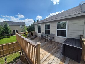 Eine Terrasse mit Gartenmöbeln, einem Grill und Blick auf eine Wohngegend.