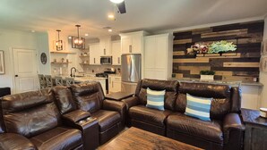 Een moderne woonkamer met lederen banken, een houten salontafel en een keuken op de achtergrond.