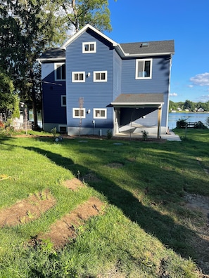 A two-story residential building with a garage, a lawn, and a lake view.