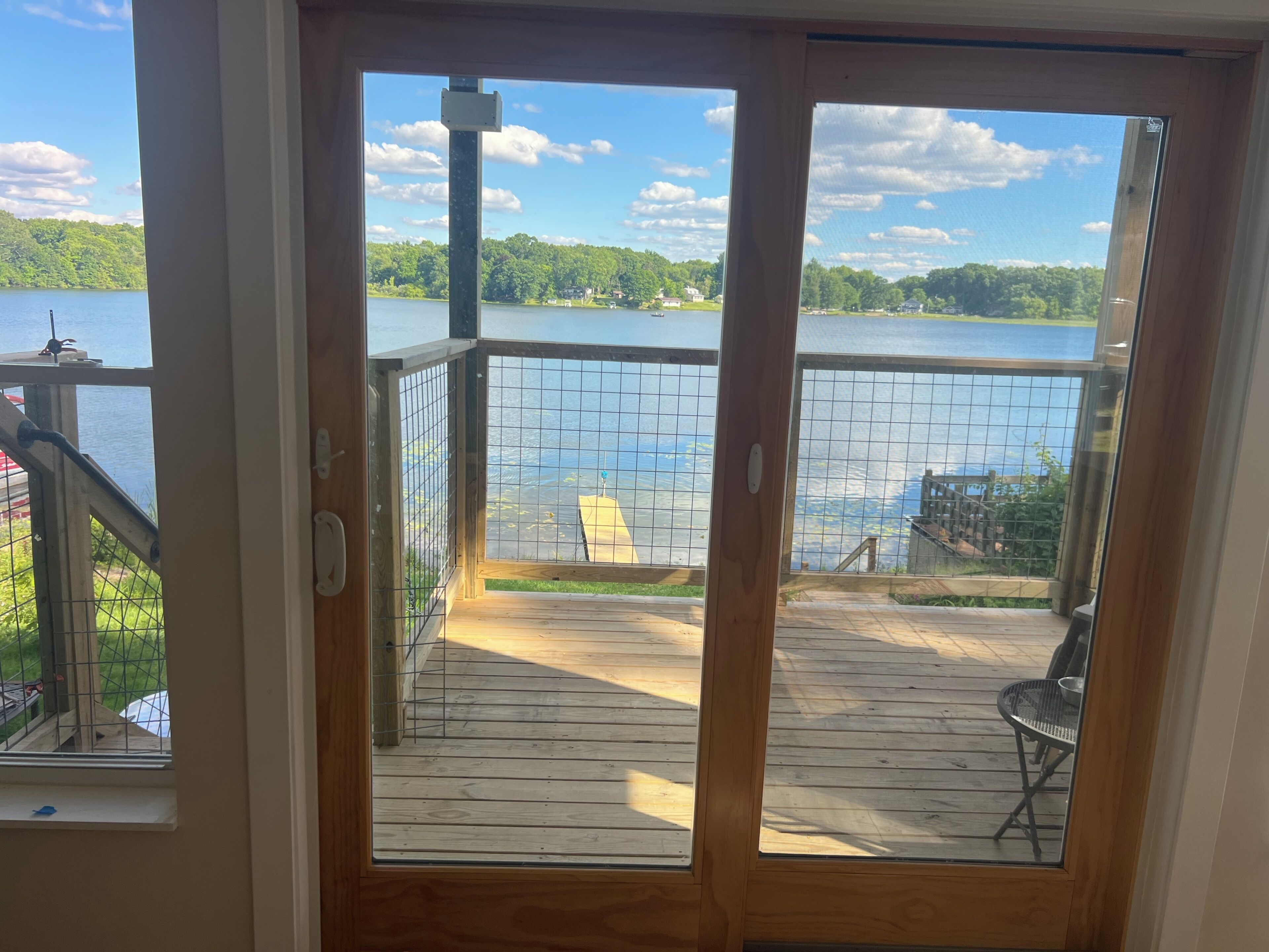A wooden deck with a view of a lake and a house in the background.