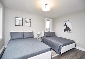 A hotel room with two beds, a window, and artwork on the walls. - This condo is perfect for families, friend groups and couples. (NIAGARA FALLS)