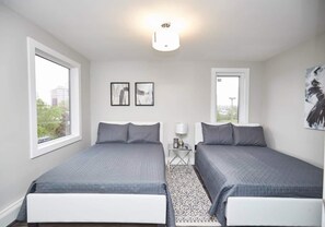A twin bedroom with two beds, a small table, and a rug.