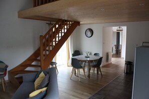 Ein geräumiger Wohnbereich mit einer Holztreppe, einem Esstisch mit Stühlen und einem Sofa.