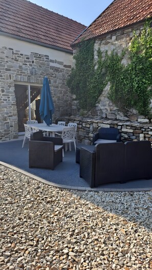 An outdoor patio with stone walls, a stone fireplace, and outdoor furniture. - Gîte "Chez Marie" - Country House in the Heart of the Cotentin (Besneville)