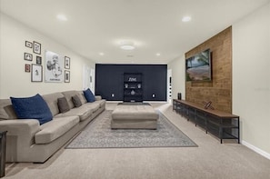 A modern living room with a sofa, ottoman, and entertainment unit. - PROMO Contemporary 8 BR Villa, Pool/Spa, Resort  - by Blue Sky Villas (Kissimmee)