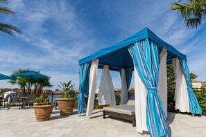 A covered outdoor seating area with a canopy, lounge chairs, and potted plants. - PROMO Contemporary 8 BR Villa, Pool/Spa, Resort  - by Blue Sky Villas (Kissimmee)