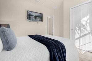 A bedroom with a bed, a painting, and a door leading to another room. - Promotion! 8BR Disney Villa | Pool, Spa, Game Room (Kissimmee)