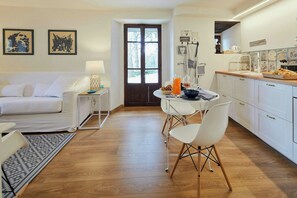 Een moderne keuken met witte kasten, een eettafel met stoelen en een koffiehoek.