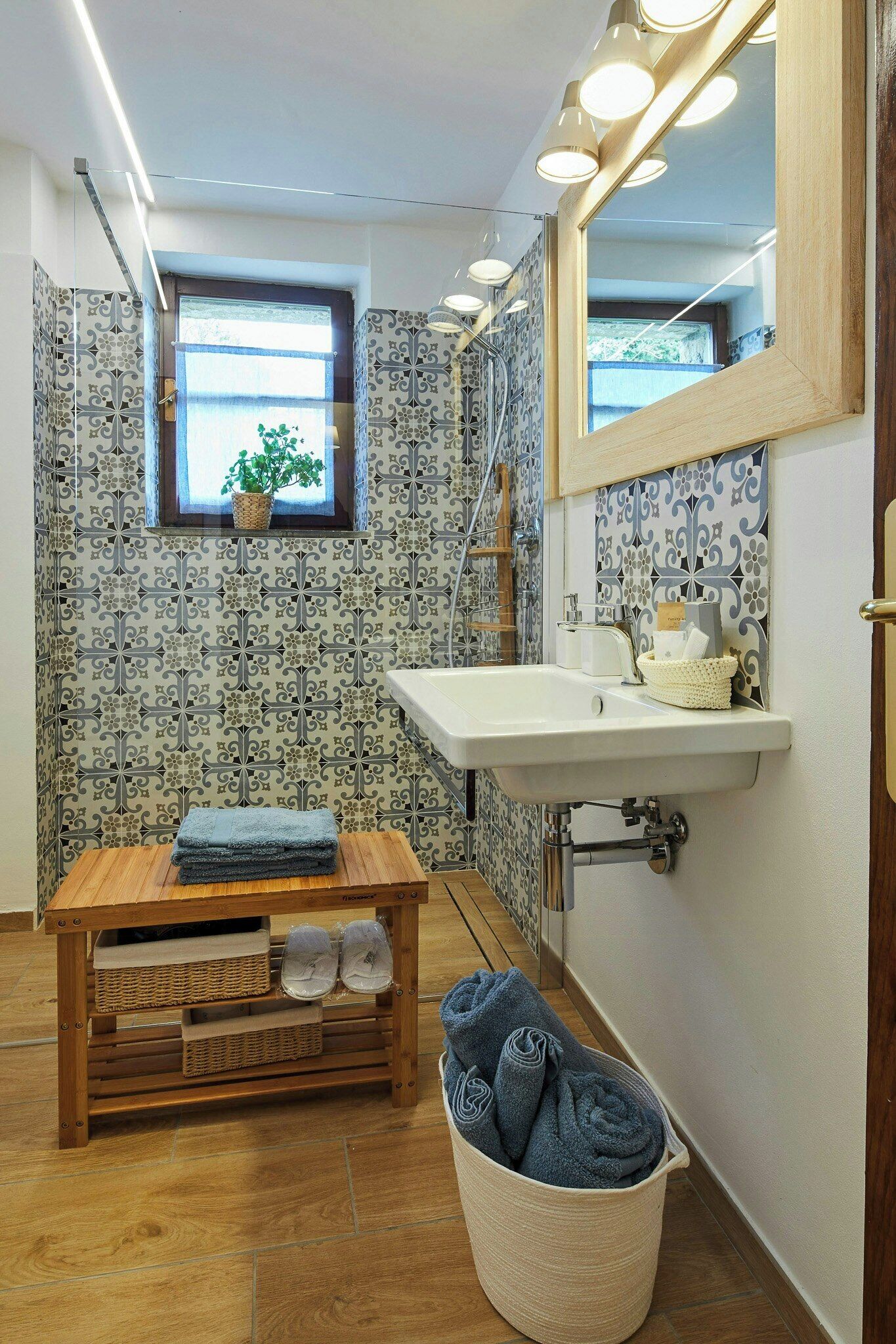 Une salle de bain avec un banc en bois, un lavabo et un miroir avec éclairage.