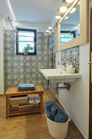 Ein Badezimmer mit einer Holzbank, einem Waschbecken und einem beleuchteten Spiegel.