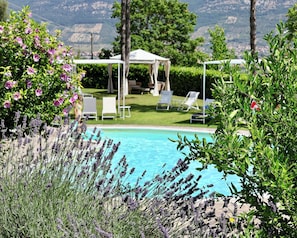 Ein Poolbereich mit Pergola, Liegestühlen und Bergblick.