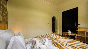 Une chambre d’hôtel avec un lit, une table ronde, une chaise, une porte et un mur orné d’un motif texturé.