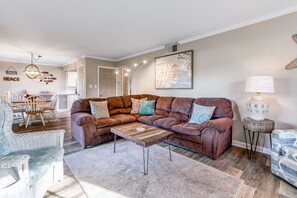 A living room with a brown sofa, a wooden coffee table, and a patterned rug. - Seascape Resort Villa | Golden Pond Pool | Minutes to the Beach! (Miramar Beach)