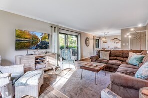 A living room with a television, a sofa, a coffee table, and wicker furniture. - Seascape Resort Villa | Golden Pond Pool | Minutes to the Beach! (Miramar Beach)