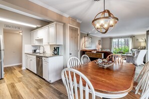 A modern kitchen with white cabinets, a wooden dining table, and a chandelier. - Seascape Resort Villa | Golden Pond Pool | Minutes to the Beach! (Miramar Beach)