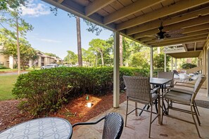 An outdoor patio area with a table and chairs, surrounded by greenery and a view of a residential street. - Seascape Resort Villa | Golden Pond Pool | Minutes to the Beach! (Miramar Beach)