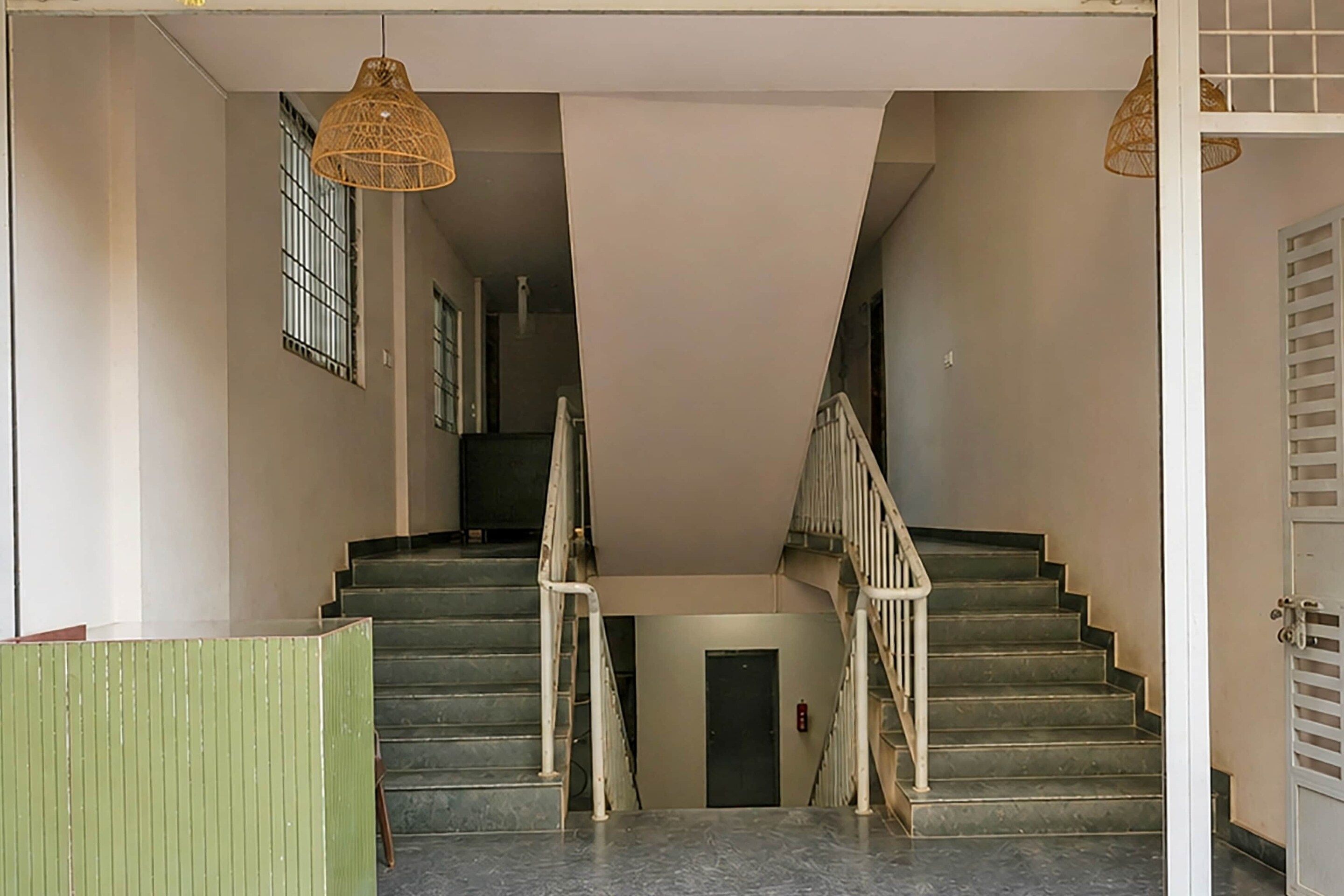 A staircase with a handrail, a door at the bottom, and a hanging light fixture.