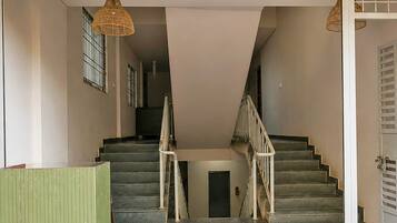 A staircase with a handrail, a door at the bottom, and a hanging light fixture.