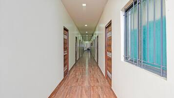 A long, narrow hallway with wooden flooring and doors on both sides.