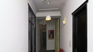 Ein Flur mit Deckenventilator, Pendelleuchte, einer Tür und einem Poster an der Wand.