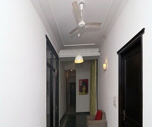 Ein Flur mit Deckenventilator, Pendelleuchte, einer Tür und einem Poster an der Wand.
