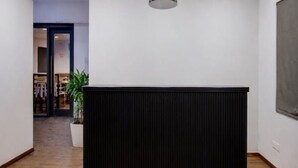 Ein Empfangsschalter in der Hotelhalle mit Holzboden, einer Topfpflanze und einer Pendelleuchte.