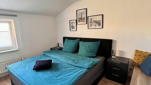 Un dormitorio con cama, mesita de noche, cómoda y ventana.
