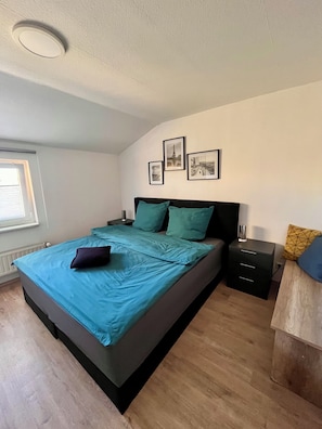 A bedroom with a bed, a nightstand, a dresser, and a window. - Westerhäuser Vacation Rentals - Bergzauber Apartment - Hiking in the Harz Mountains (Thale)