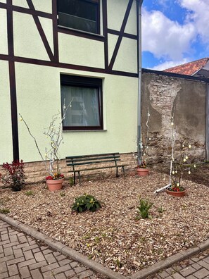 A building with a stone wall and a wooden bench in the foreground. - Westerhäuser Vacation Rentals - Bergzauber Apartment - Hiking in the Harz Mountains (Thale)