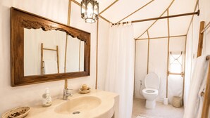 Un baño con un espejo de marco de madera, un lavabo color beige y una lámpara colgante.