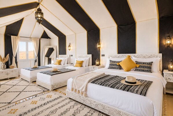 Un dormitorio estilo tienda de lujo con dos camas, almohadas decorativas e iluminación ambiental.
