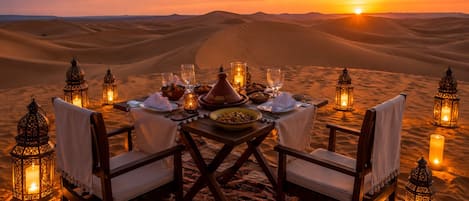 A desert dinner setup with a table, chairs, and candles.