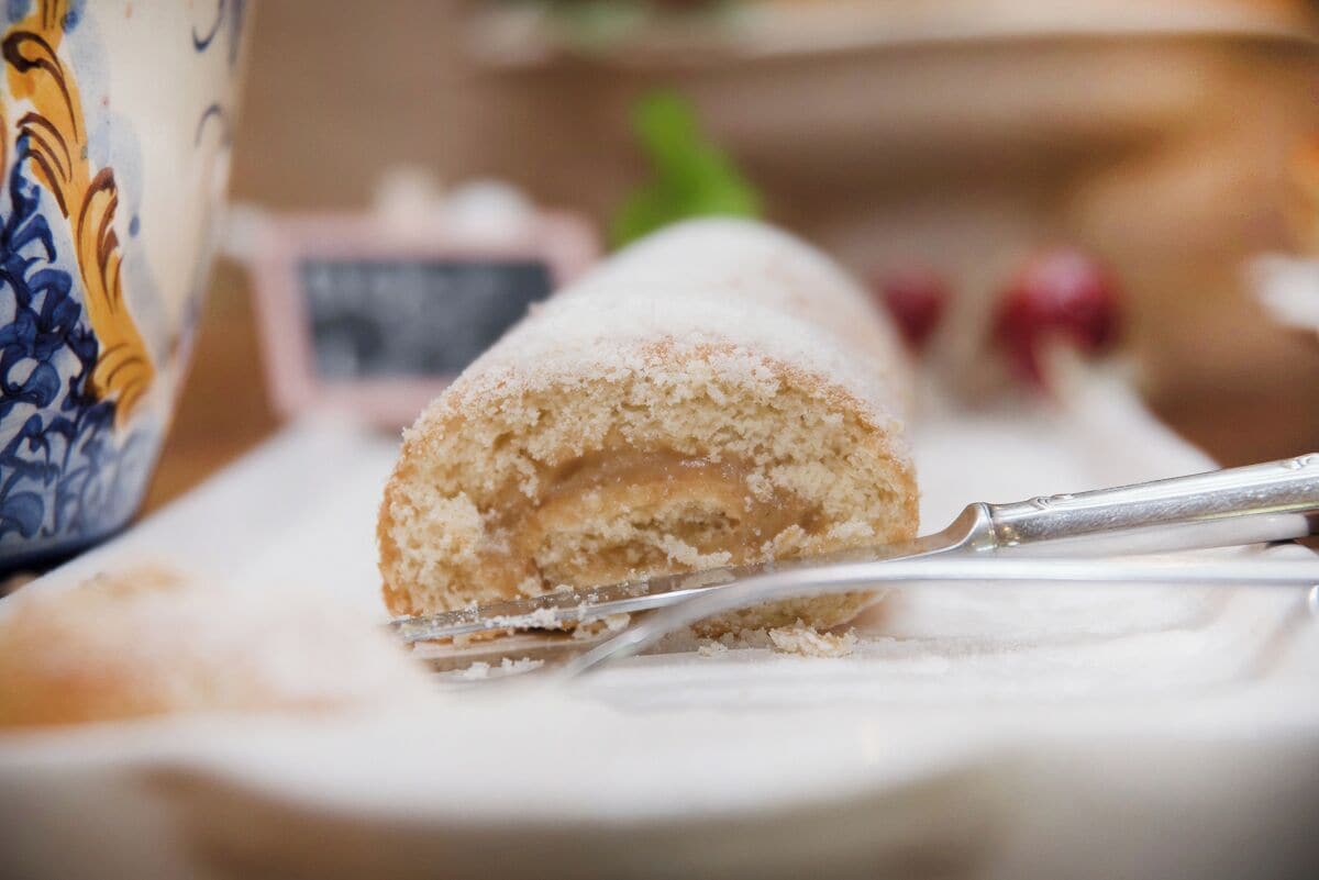 A rolled pastry on a white plate with a fork.