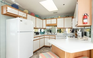 A compact kitchen with a refrigerator, stove, sink, and wooden cabinets. - Phoenix V 1407 1 Bedroom Condo (Orange Beach)
