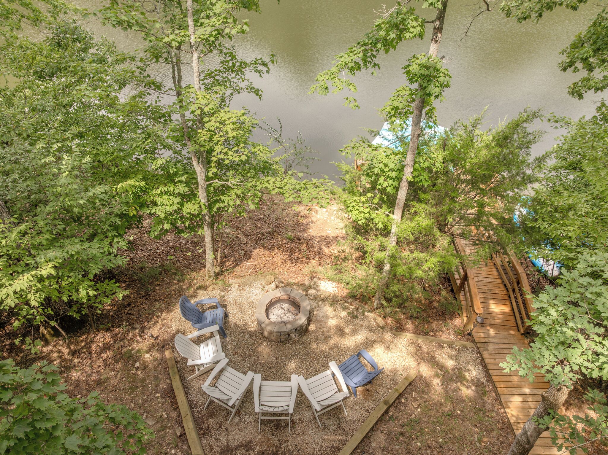 A campsite with a fire pit, wooden deck, and Adirondack chairs.