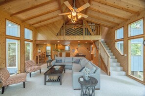 A spacious living area with a high ceiling, a staircase, and large windows. - Lakefront Retreat by Innsbrook Vacations! (Innsbrook)