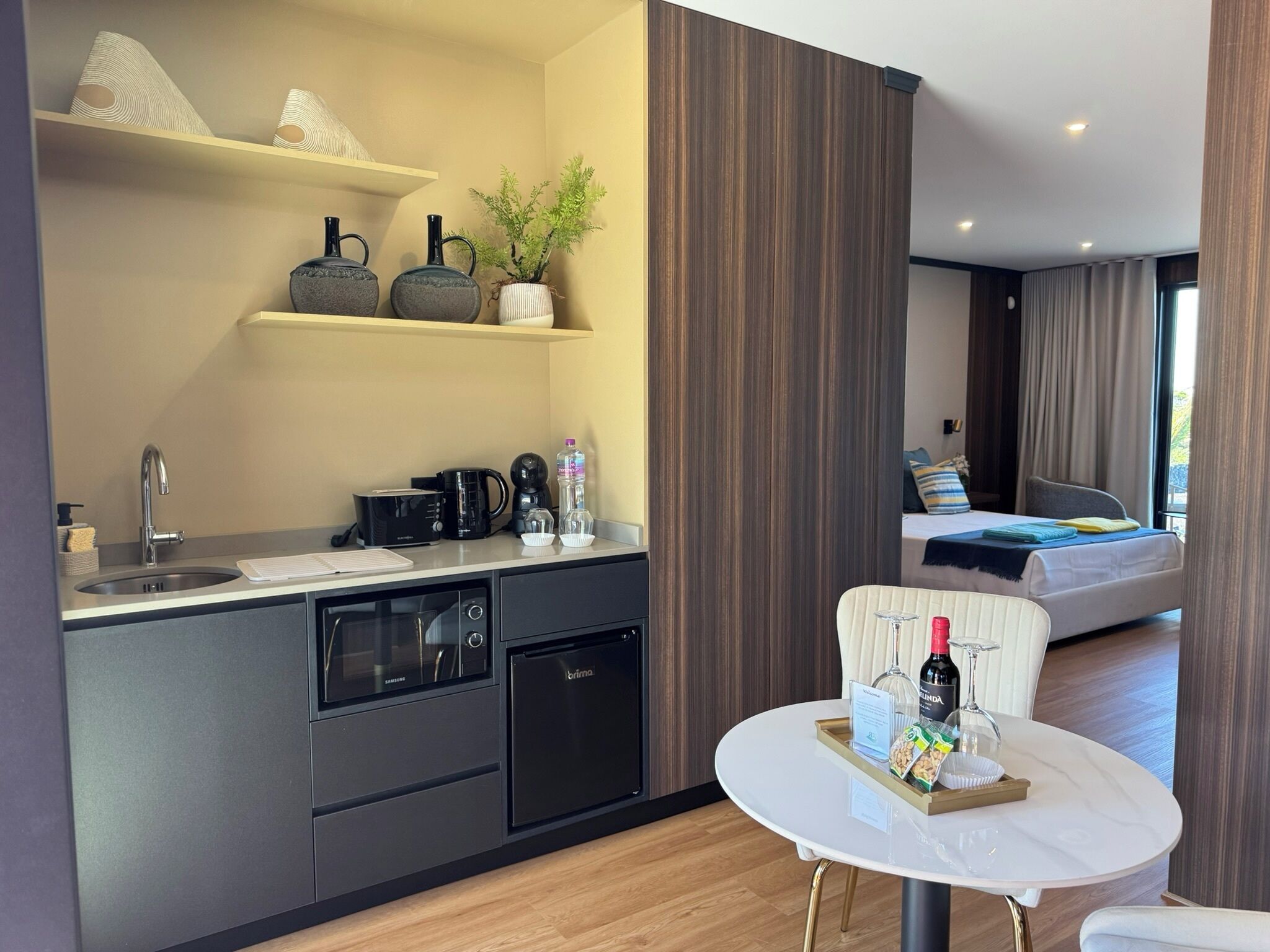 A modern kitchenette with a built-in oven, a coffee maker, and a water dispenser.