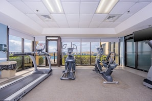 Un gimnasio con cintas de correr, elípticas y una bicicleta estática.