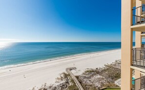 A beachfront view from a balcony overlooking a sandy beach with a clear blue sky. - Phoenix I 1106 1 Bedroom Condo (Orange Beach)